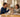 Parent handing a flip phone to an excited teenager at a kitchen table
