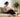 Woman reading a book on a sofa with her phone set aside in afternoon sunlight