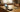 Cheap prepaid flip phone open on a wooden table beside cash and a coffee mug