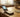 Cheap prepaid flip phone open on a wooden table beside cash and a coffee mug
