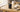 Compact MP3 player without WiFi sitting on a wooden desk beside wireless earbuds in soft morning light